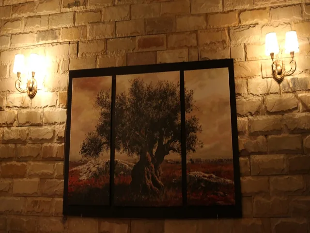 Olivenbaum auf drei Bildern an der Backsteinwand zwischen Wandlampen