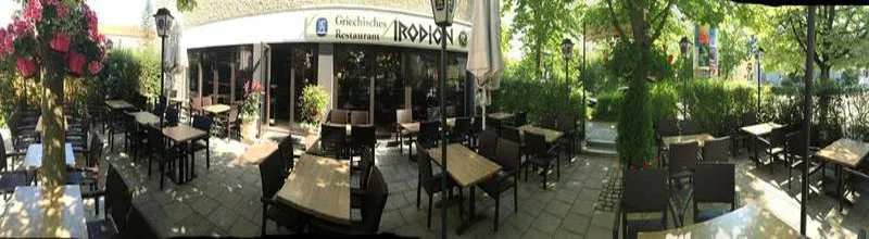 Terrasse mit Eingang und Schild Irodion, breite Ansicht